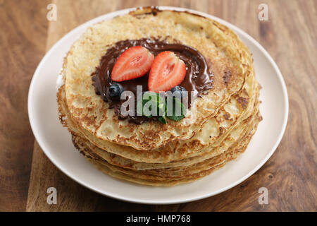 frische Blinis oder Crepes mit geschmolzener Zartbitterschokolade und Beeren Stockfoto