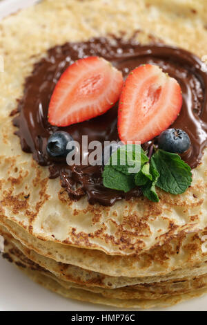 frische Blinis oder Crepes mit geschmolzener Zartbitterschokolade und Beeren Stockfoto