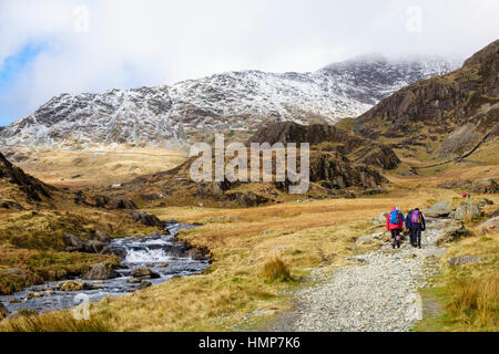 Wanderer auf Watkin Path Route zu Snowdon Wandern neben Afon Cwm Llançà Fluss im Winter. Cwm Llançà Gwynedd Snowdonia National Park (Eryri) Wales UK Großbritannien Stockfoto