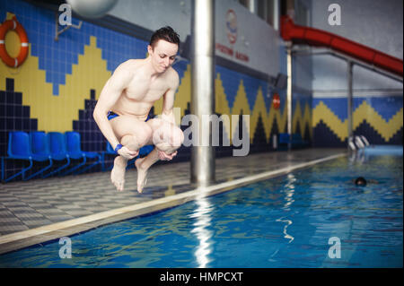 Mann springt im Schwimmbad Stockfoto