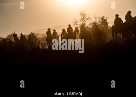 Hunderte von mexikanischen Cowboys sind von der aufgehenden Sonne während der jährlichen Wallfahrt Cabalgata de Cristo Rey 5. Januar 2017 in San José del Rodeo, Guanajuato, Mexiko Silhouette. Tausende von mexikanischen Cowboys und Pferd beteiligen sich die drei-Tages-Fahrt zum Berggipfel Schrein des Cristo Rey stoppen auf dem Weg an Schreinen und Kirchen. Stockfoto