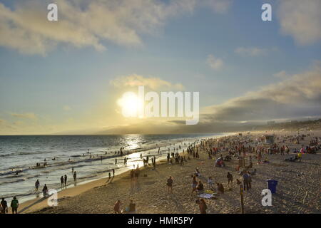 Strand von Santa Monica in Kalifornien bei Sonnenuntergang mit goldenen Himmel und Wolken am Wochenende überfüllt Stockfoto