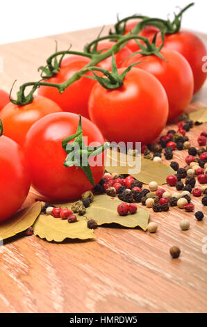 Cherry-Tomaten mit schwarzem Pfeffer und Lorbeerblatt auf dem hölzernen Hintergrund Stockfoto