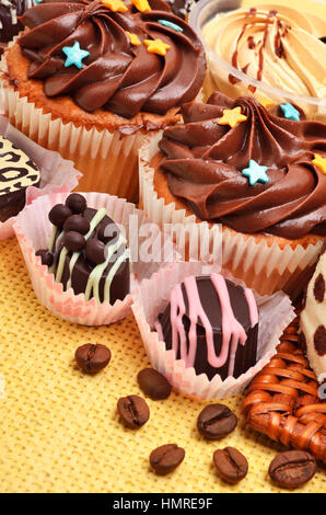 Сhocolate Süßigkeiten, Muffins und Kaffeekörner auf der Tischdecke Stockfoto