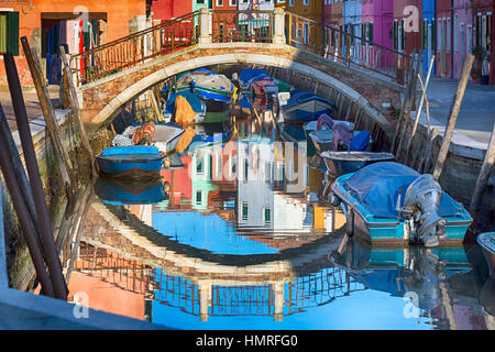 Bunte Reflexionen von Häusern mit Booten und Brücke in Burano - leuchtenden Farben der Burano, Venedig, Italien im Januar Stockfoto