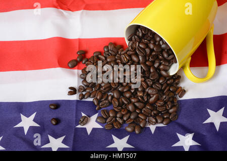 Kaffee Bohnen verschütten aus gelben Tasse auf USA-Flagge. Stockfoto