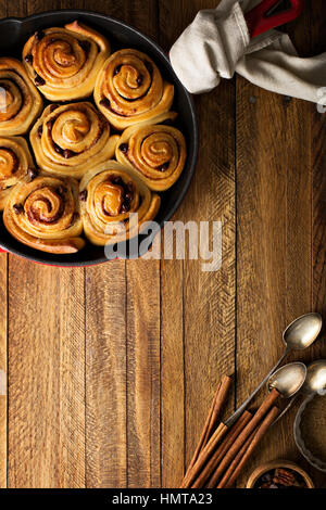 Zimtschnecken mit Schokostückchen gebacken in einer gusseisernen Pfanne über Kopf gedreht Stockfoto