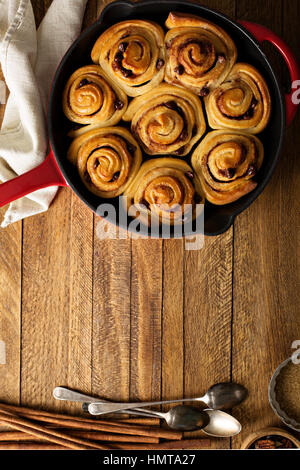 Zimtschnecken mit Schokostückchen gebacken in einer gusseisernen Pfanne über Kopf gedreht Stockfoto