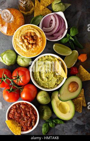 Hausgemachter Hummus, Salsa und Guacamole mit Mais-Chips und Gemüse Draufsicht Stockfoto