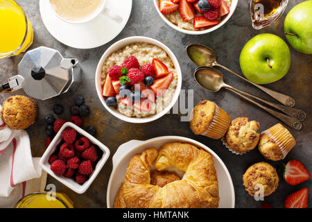 Frühstückstisch mit Haferflocken Brei, Croissants, frischem Obst und Muffins über Kopf gedreht Stockfoto