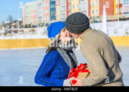 Mann gibt seine Freundin Überraschung Geschenk für einen Urlaub und Küsse. Stockfoto