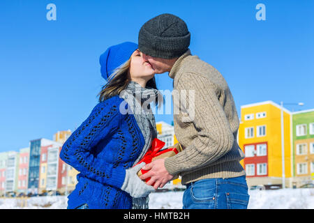 Mann gibt seine Freundin Überraschung Geschenk für einen Urlaub und Küsse. Stockfoto