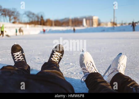 Männlichen und weiblichen Füße in Schlittschuhe haben eine Pause auf Ice Rink Oberfläche. Konzept macht Spaß Outdoor Wintersport Stockfoto