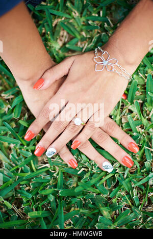 Hand mit lackierten Nägel auf dem grünen Rasen Stockfoto