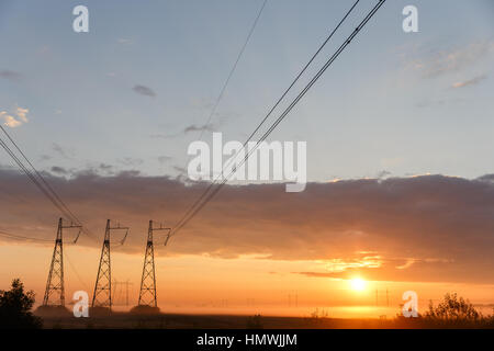 Stromleitungen auf lila Himmel bei Sonnenuntergang Stockfoto