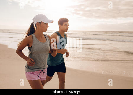 Junges Paar zusammen am Strand laufen. Im Freien Schuss des jungen Paares auf Morgenlauf. Stockfoto