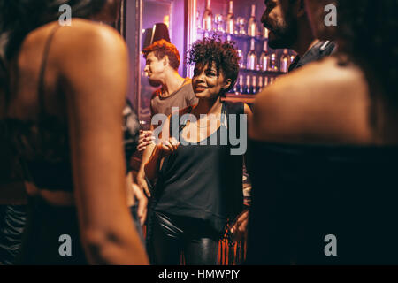 Schöne junge Frau mit ihren Freunden im Nachtclub. Junge afrikanische Frau mit Freunden im Pub. Stockfoto