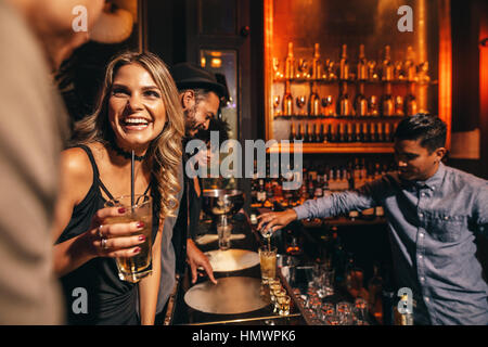 Schöne junge Frau mit ihren Freunden am Bar. Junge Menschen genießen Sie eine Nacht im Club. Stockfoto