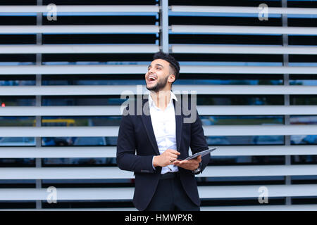 Unternehmer nutzt Tablet bei Online-Bestellung, shopping mit Debit Kreditkarte aussehende Lächeln in die Kamera. Junge hübsche Geschäftsmann arabische Muslime in bu Stockfoto