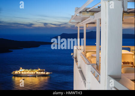 Erleuchtete Kreuzfahrtschiff nach Sonnenuntergang in der Nähe der Stadt Fira auf Santorin, Griechenland Stockfoto