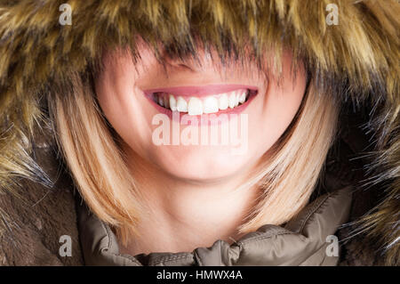 Nahaufnahme von blonden Mädchen mit Kunstpelz Kapuze mit Augen bedeckt bin glücklich lächelnd. Stockfoto