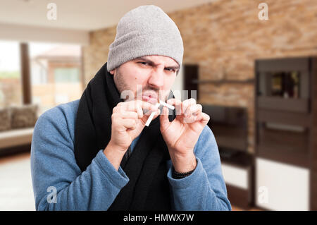 Junger Mann brechen Zigarette in zwei Stücke als Stop-Smoking-Konzept Stockfoto