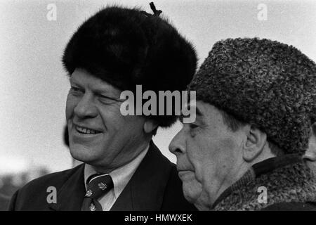 US-Präsident Gerald Ford ein Russe tragen Pelz Hut mit sowjetischen Generalsekretär Leonid Brezhnev bei der Ankunft am lang Airbase 23. November 1974 in Wladiwostok, Russland, UdSSR. Ford ist in Wladiwostok zu einem zweitägigen Gipfel über Rüstungskontrolle. Stockfoto