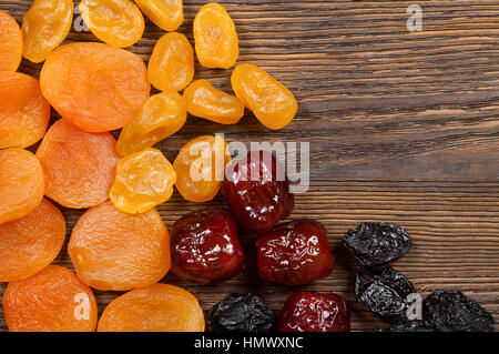 Getrocknete Früchte auf einem hölzernen Hintergrund. Aprikosen, Datteln, Zitronen und Pflaumen. Stockfoto