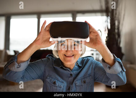 Ältere Frau mit virtual-Reality Brille zu Hause Stockfoto