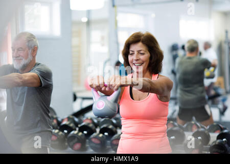 Älteres Paar im Fitness-Studio trainieren mit Kettlebells. Stockfoto