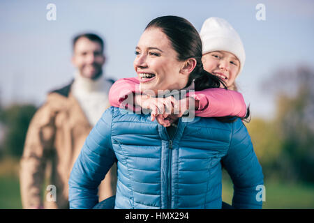 Fröhliche Mutter Huckepack Töchterchen Stockfoto