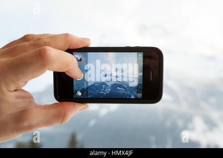 GRINDELWALD, Schweiz - 4. Februar 2014: Mann ein Foto von den Eiger mit der Kamera-app auf einem Apple iPhone 4 s. Close-up erschossen von der Stockfoto