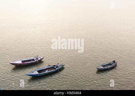 VARANASI, Indien - 5. Januar 2015: Drei Männer Ruderboote am Fluss Ganges. Stockfoto