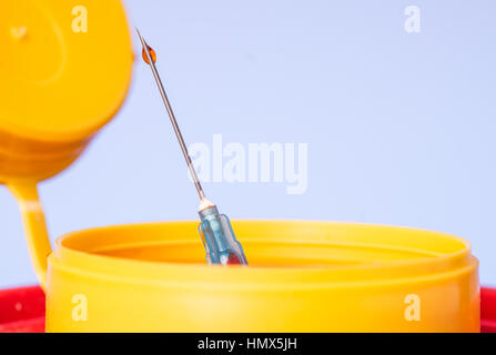 Gelbe medizinische Nadel Entsorgung Abfallbehälter, Spritzennadel mit roten Tropfen an der Spitze. Isoliert Stockfoto