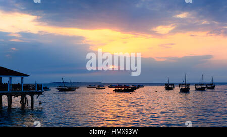 Typische Boote im Hafen von Stone Town, Sansibar, Tansania Republik am Sonnenuntergang verankert. Stockfoto