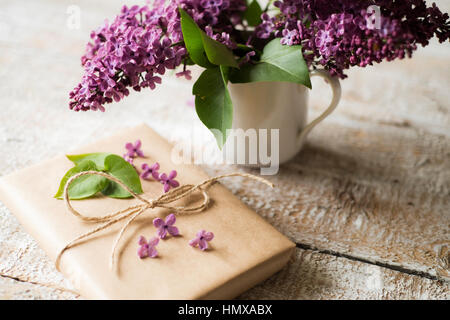 Lila lila Blumenstrauß in Vase und Gegenwart auf Holztisch gelegt. Stockfoto