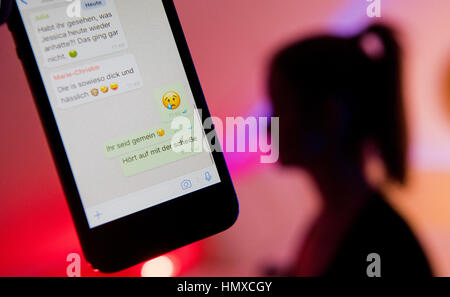 ILLUSTRATION - ein junges Mädchen im Display eines Smartphones mit Chat Dialog Containting Beleidigungen innerhalb der Bote "WhatsApp" in Hannover, 4. Februar 2017. Die offizielle Bezeichnung für Verbreitung falscher Informationen oder Beleidigung von Personen "Cybermobbing" ist der 7. Februar Safer Internet Day mit einem Fokus auf Cybermobbing.     (Inszenierten Szene) Foto: Julian Stratenschulte/dpa Stockfoto