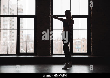 Silhouette der Sportlerin stehend und Schatten Boxen Übungen am Fenster Stockfoto