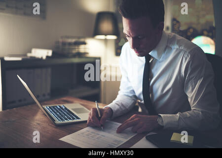 Geschäftsmann Arbeiten konzentrierten sich auf Dokumente in der Nacht, Überstunden im Büro Stockfoto