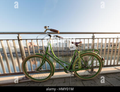 Düsseldorf, Deutschland - 20. Januar 2017: Ein grünes Fahrrad auf den Handlauf im New Media Hafen lehnt Stockfoto