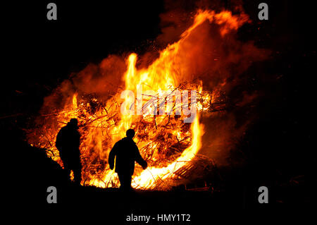 Silhouetten von Personen vor einem großen Osterfeuer. Stockfoto