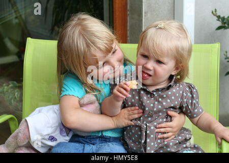 Schwestern umarmen, zusammen sitzen Garten Schwesternliebe, Geschwister Verbindung Familie Liebe, Freude gemeinsam miteinander, die besten Freunde, besties Stockfoto