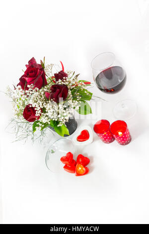 Zusammensetzung eines Valentines Day Rose Bouquet Rotwein und Herz geformt Kerzen auf weißem Hintergrund-Porträt-Draufsicht Stockfoto