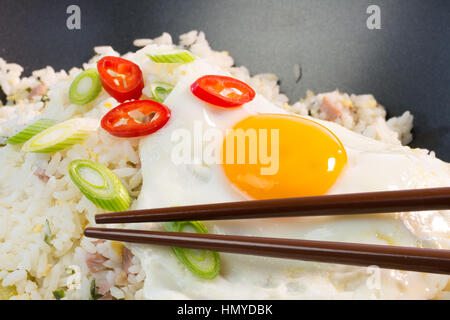 Indonesische Nasi Goreng (gebratener Reis) mit Spiegelei und Stäbchen Stockfoto