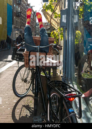 Fahrrad lehnte sich gegen ein Fenster mit dummy Beine kleben aus dem Korb Stockfoto