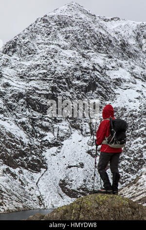Weibliche Walker im rote Jacke mit Blick auf die Ostwand des Snowdon in Snowdonia-Nationalpark im Norden von Wales. Stockfoto