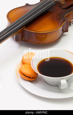 Musik-Pause - alte Geige, Tasse Kaffee und traditionellen französischen bunten Macarons auf dem weißen Tisch Stockfoto