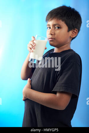 mollig Latino Boy trinken Milch isoliert auf blau Stockfoto