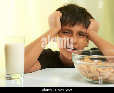 lustige junge auf Frühstück mit Milch und Getreide auf gelb isoliert Stockfoto