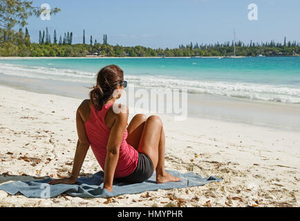 eine Frau sitzt an einem tropischen Strand auf Ile des Pins in Neu-Kaledonien Stockfoto
